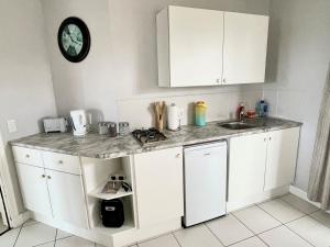 eine Küche mit weißen Schränken und einer Arbeitsplatte in der Unterkunft San Lukas Guest Apartment in St Francis Bay