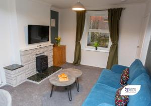 a living room with a blue couch and a fireplace at Luke Stays - Good Station Cottages in Durham