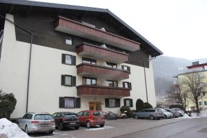 a building with balconies and cars parked in a parking lot at Dachgeschoss-Apartment in Skilift-Nähe in Zell am See