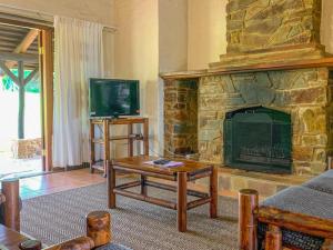 a living room with a stone fireplace and a tv at Swallowfield Estate 7 & 12 Wits End in Winterton