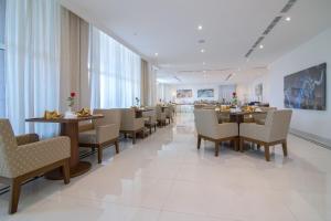 a dining room with tables and chairs and windows at The Gate Hotel and Apartments in Dammam