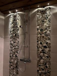 a shower in a bathroom with a stone wall at Välituvan lomamökit in Punkaharju