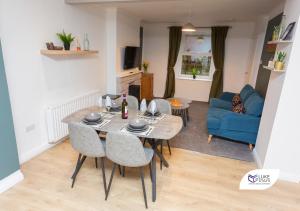 een woonkamer met een tafel en stoelen en een blauwe bank bij Luke Stays - Good Station Cottages in Durham