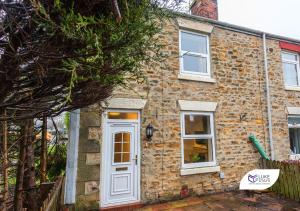 una casa in mattoni con una porta bianca di Luke Stays - Good Station Cottages a Durham