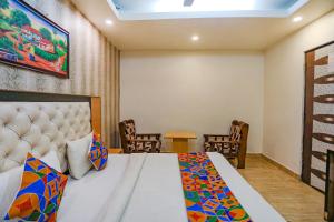 a bedroom with a bed with chairs and a table at FabHotel Joy Stick, Sector 11 Noida in Indirapuram