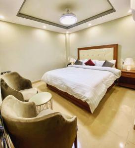 a bedroom with a bed and two chairs in it at Grand Luxury Hotel Multan in Multan