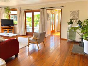 a living room with wood floors and a living room with a table at Peaceful House with Kids Playground in Motueka