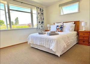 a bedroom with a white bed with a window at Peaceful House with Kids Playground in Motueka