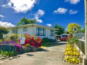 a house with flowers in front of it at Peaceful House with Kids Playground in Motueka