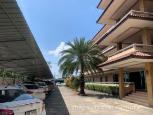 een palmboom voor een gebouw met geparkeerde auto's bij Tharapark View Hotel - SHA Plus in Krabi town