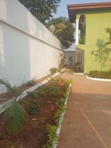 a side yard of a house with a white wall at PN Meublés FULL OPTION Odza Dispose d'une voiture et un chauffeur gratuitement de l,aéroport aux appartements pour des réservations minimum de 7 jours in Yaoundé
