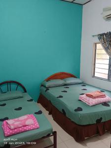 twee bedden in een kamer met blauwe muren bij EMBUN 2 LANGKAWI HOMESTAY in Pantai Cenang