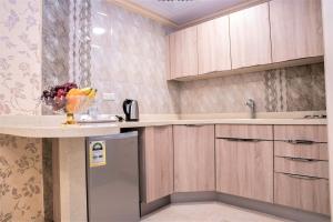 a kitchen with wooden cabinets and a bowl of fruit on a counter at سارة للشقق المخدومة Sara Serviced Apartments in Al Khobar