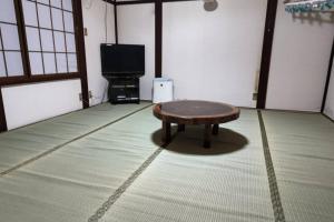 a room with a coffee table and a flat screen tv at Ohanabatake in Tsuruoka