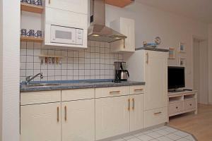 uma cozinha com armários brancos, um lavatório e um micro-ondas em Haus Weisse Möwe Weisse Möwe 3 em Cuxhaven