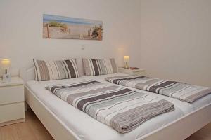 a white bed with two blankets on top of it at Haus Weisse Möwe Weisse Möwe 3 in Cuxhaven