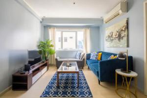 ein Wohnzimmer mit einem blauen Sofa und einem Tisch in der Unterkunft BGC Private Apartments in Manila