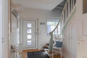 korytarz ze schodami z dwoma krzesłami i drzwiami w obiekcie Haus im Kreuzweg CASA Blanca 2 w mieście Cuxhaven