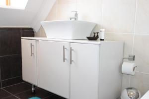 baño con lavabo y armario blanco en Blue Crane Guesthouse en Maseru