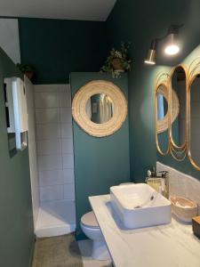 a bathroom with a sink and a toilet and a mirror at La Chaise Haute in Hagetmau