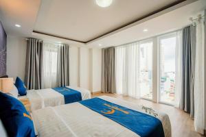 ニャチャンにあるMoonlight Nha Trang Hotelのベッドが2つと大きな窓があるホテルの部屋