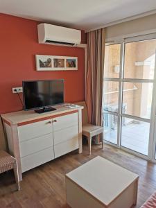 salon z telewizorem z płaskim ekranem na komodzie w obiekcie APPARTEMENT CAP ESTEREL CLIMATISE VUE MER w mieście Agay - Saint Raphael