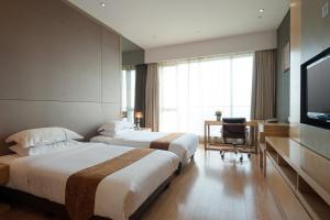 a hotel room with two beds and a television at Yicheng Pazhou Poly World Trade Centre Apartment in Guangzhou