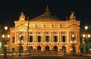 duży budynek jest oświetlony w nocy w obiekcie Hotel Mogador w Paryżu