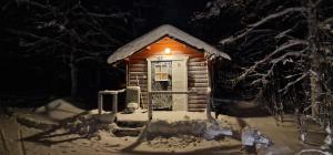 a small wooden cabin covered in snow at night at Hamra Stugby - Nature Adventures Hamra in Hamra