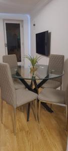 a glass dining room table with chairs and a television at Lovely 2 bedroom Flat with Free Parking in New Southgate