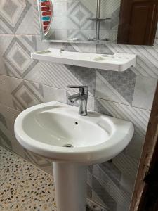 a bathroom with a white sink and a mirror at Appartement New Stading YAOUNDE - MIMBOMAN MAETURE in Yaoundé