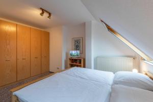 a bedroom with a large white bed and a tv at Haus Relax Appartements Duhnen Haus Relax Appartements Duhnen - Wohnung 2 in Cuxhaven