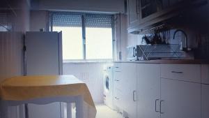 eine Küche mit einem weißen Kühlschrank und einem Fenster in der Unterkunft GG Massamá Rooms in Queluz
