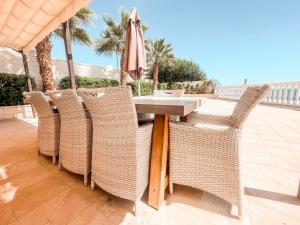 a table with wicker chairs and an umbrella on a patio at Villa Julia in Callao Salvaje in Callao Salvaje