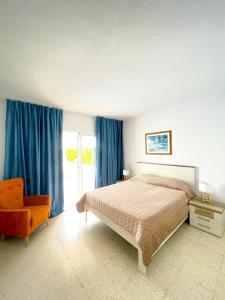 a bedroom with a bed and a chair and blue curtains at Villa Julia in Callao Salvaje in Callao Salvaje