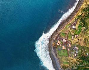 an aerial view of a house on the shore of the ocean at Kuanza Nature Experience, Fajã do Belo in Fajã da Caldeira de Santo Cristo