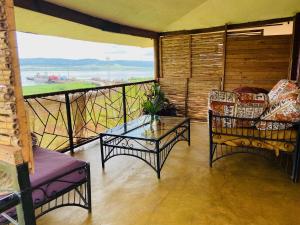 een kamer met 2 stoelen en een glazen tafel op een balkon bij Home On The Nile Ernest Hemingway Suite in Jinja
