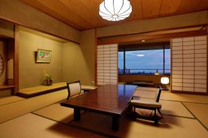 uma sala de jantar com uma mesa de madeira e cadeiras em Sakahijiri gyokushoen em Izu
