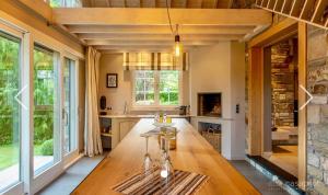 a kitchen with a large wooden table and large windows at Côté Mont in Malmedy