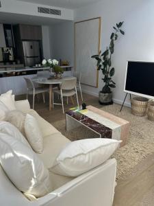 uma sala de estar com um sofá branco e uma televisão em New & Modern Loft 1bd w/Pool&Gym em Camberra