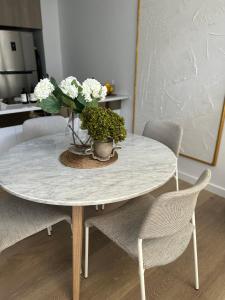 a white table with a vase of flowers on it at New & Modern Loft 1bd w/Pool&Gym in Canberra