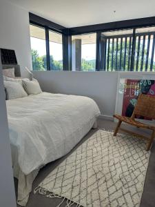 1 dormitorio con 1 cama, 1 silla y ventanas en New & Modern Loft 1bd w/Pool&Gym, en Canberra
