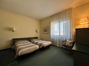 a hotel room with two beds and a window at Hotel La Goletta in Binasco