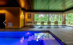 a swimming pool in a room with chairs and a table at Côté Mont in Malmedy