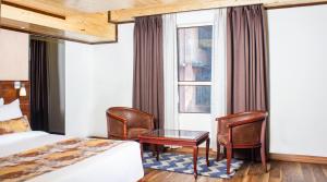 a hotel room with a bed and chairs and a window at Yashshree Mall Road Darjeeling in Darjeeling