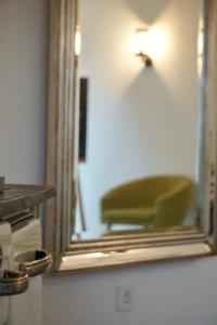 lustro z zielonym krzesłem w pokoju w obiekcie Landhotel Strandallee w mieście Wunstorf