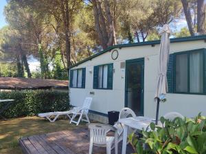 a white caravan with a table and chairs and an umbrella at Toscana Holiday Village in Montopoli in Val dʼArno