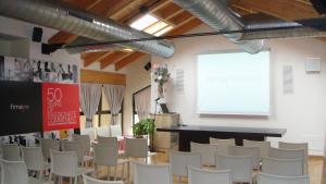 a room filled with white chairs and a projection screen at Il Bucchio Country Hotel in San Giovanni in Persiceto