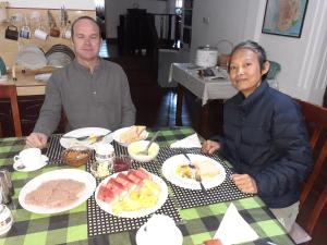 Dois homens sentados numa mesa com pratos de comida. em Kandy Mountain Cottage em Kandy