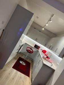 a white kitchen with a red stool in the middle at Modern 2bedrooms in woolwich in Woolwich